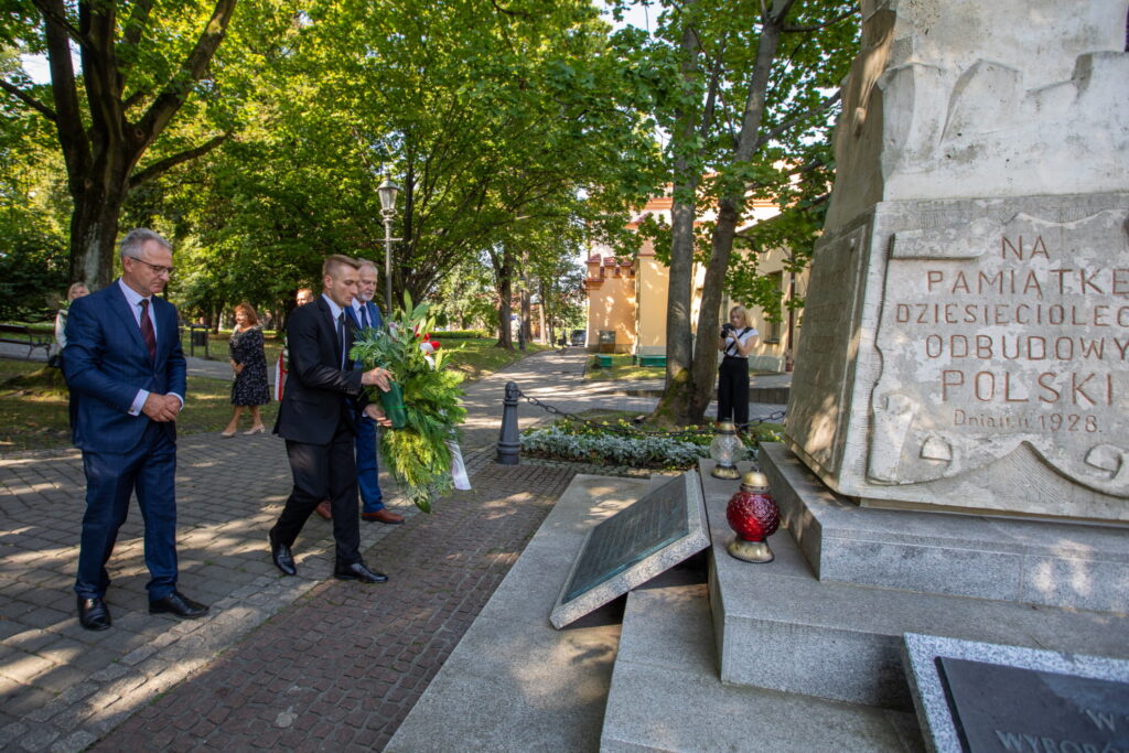 Delegacja składająca kwiaty. Po Prawej stronie kadru fragment pomnika na wielickich Plantach